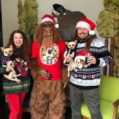 Big Foot Santa posing for the photo with a couple of guests and their dogs