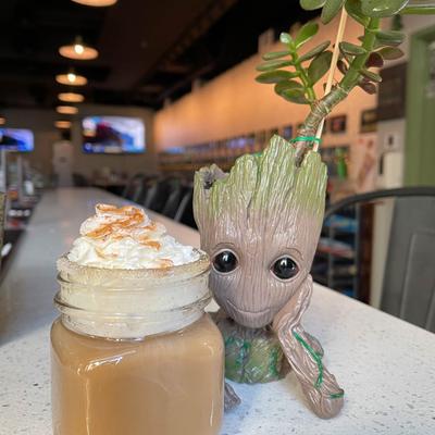 Iced Coffee on the bar counter, next to a Baby Groot plant pot