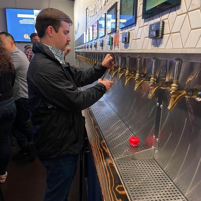 A customer pouring a beer from beer tap wall